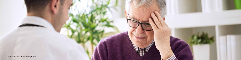 Älterer Mann mit chronischen Spannungskopfschmerzen sitzt beim Arzt.