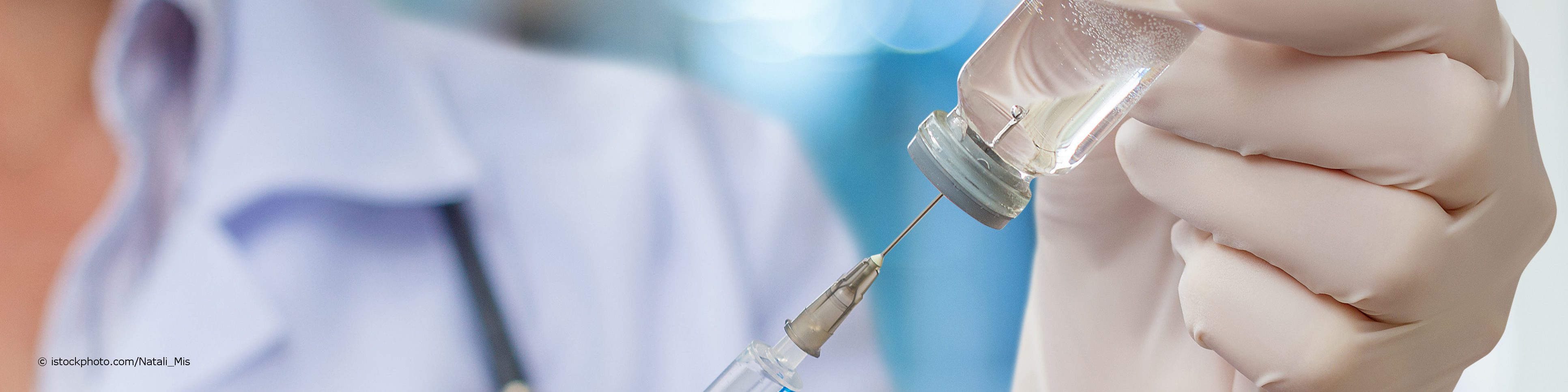 Arzt zieht Spritze mit Impfstoff zur Grundimmunisierung auf.